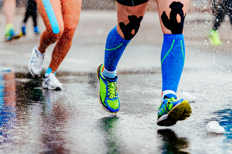 Бегущие спортсмены с тейпами на ногах